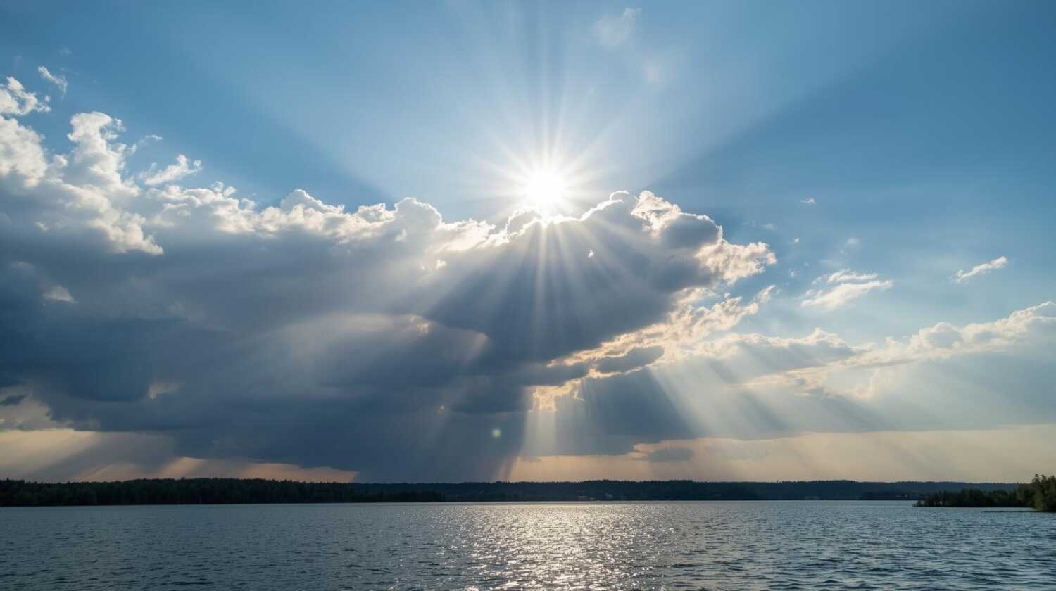 湖畔の水辺、空は曇っているが、雲の切れ間から朝日が強く差し込んでいる