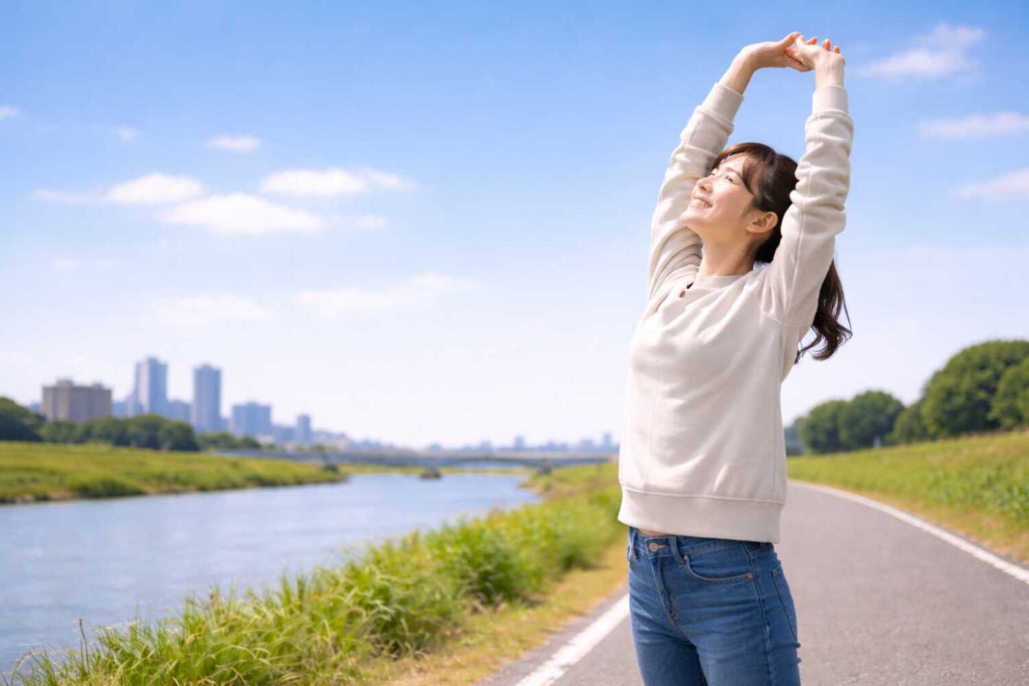 川沿いの道、気持ち良さそうに伸びをする女性